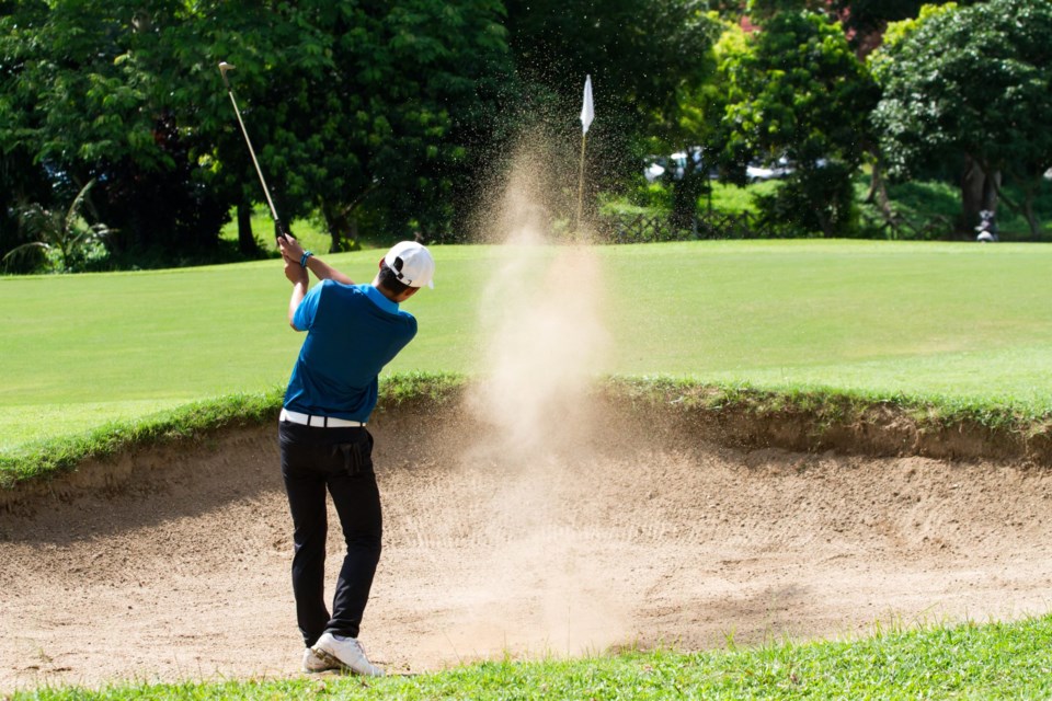 Young,Man,Golf,Player,In,Action,Swing,In,Sand