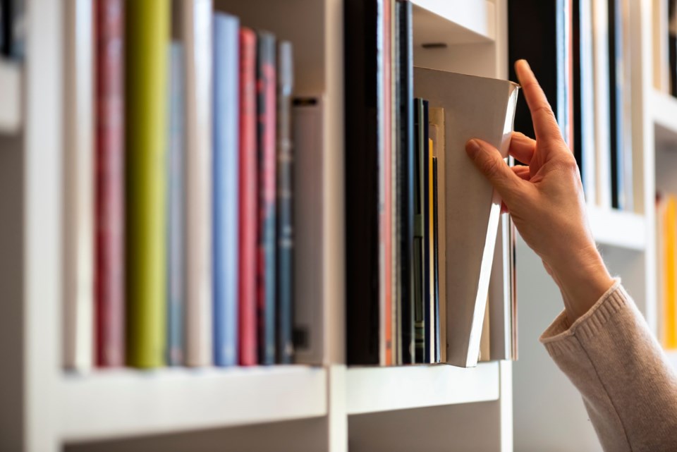 Hand,Of,Woman,Searching,For,A,Book,On,Shelf