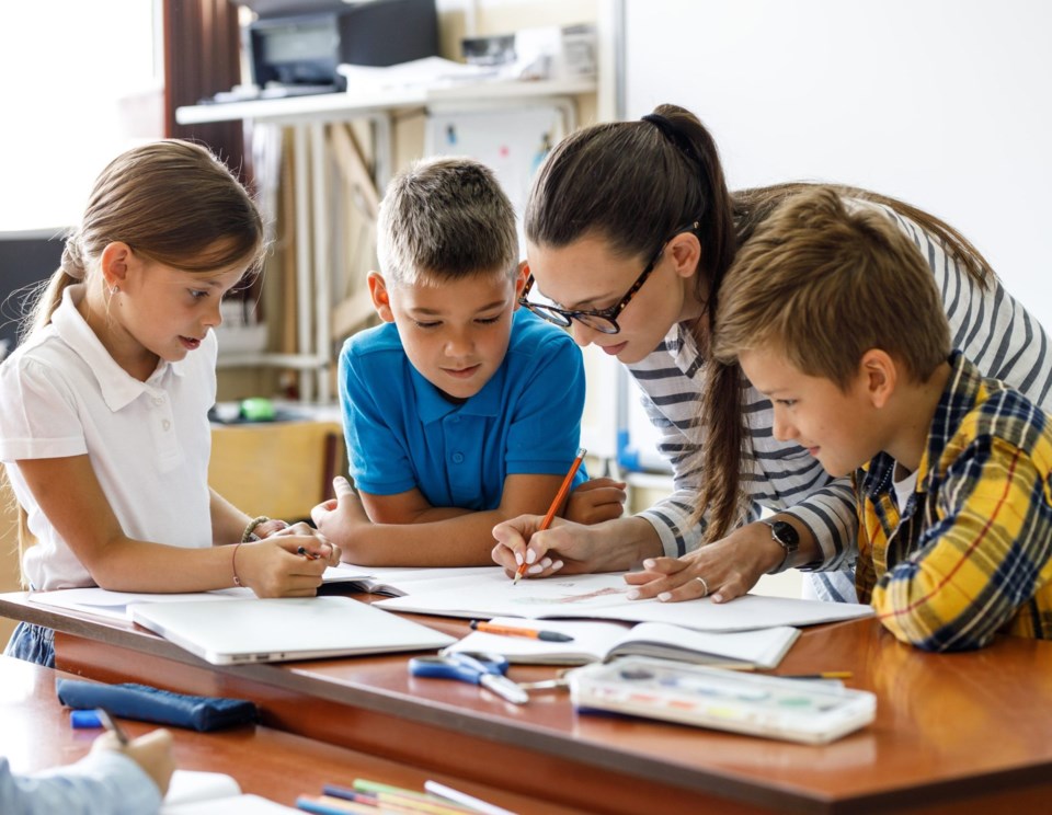 Female,Teacher,Helps,School,Kids,To,Finish,They,Lesson.they,Sitting