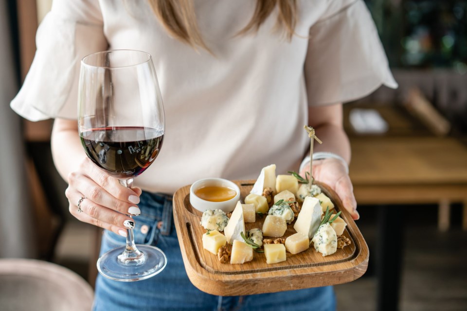 Girl,Holding,Glass,Red,Wine,And,Wooden,Plate,With,Cheese.