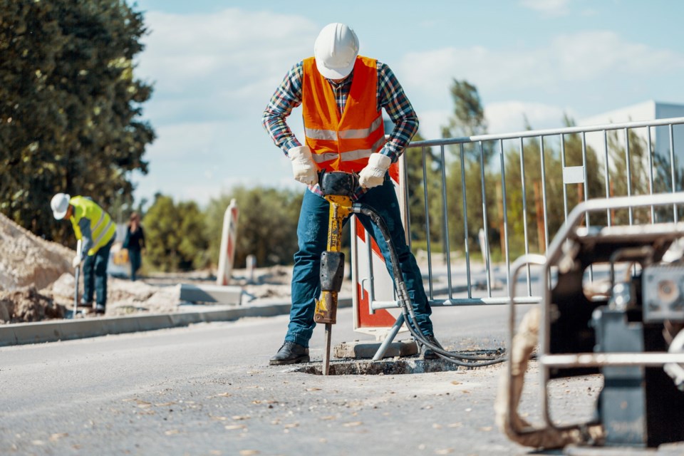 Worker,In,Reflective,Vest,With,Drill,Repairing,Street,During,Roadworks