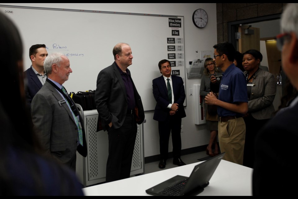Colorado Treasurer Dave Young and Gov. Jared Polis listen as a student explains the Innovation Center's work in cybersecurity.