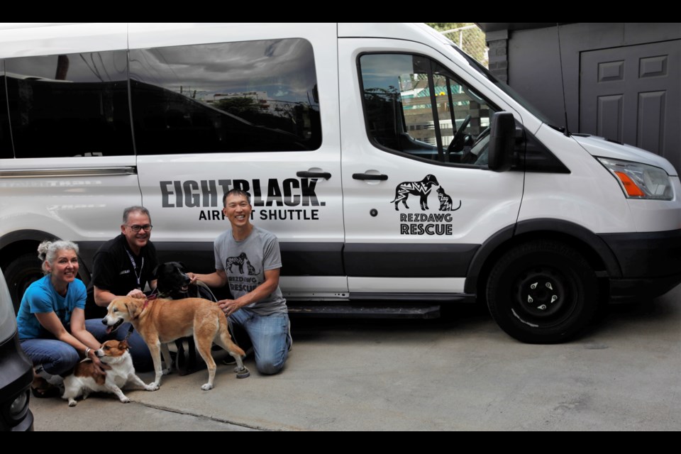 Rezdawg Rescue volunteers Dorian Macdonald and Hsun Chen, left and right, pose with their rescue dogs and new van, donated to them by Eight Black Airport Shuttle and owner Simon Chen, center.
