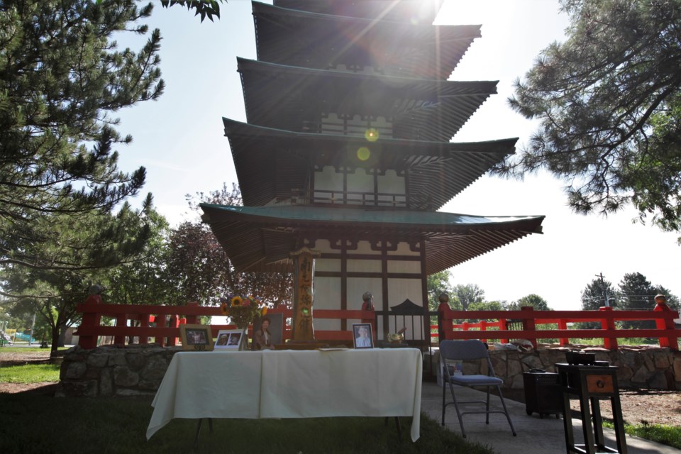 Photos of loved ones are set out in front of the Tower of Compassion during the Obon celebration at Kanemoto Park on Sunday.