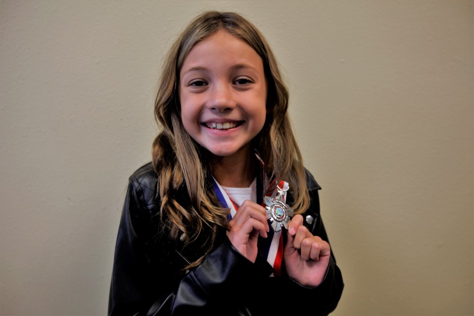 Bella Johnson shows off her Lifesaving Award at a ceremony recognizing her efforts to save her mother.