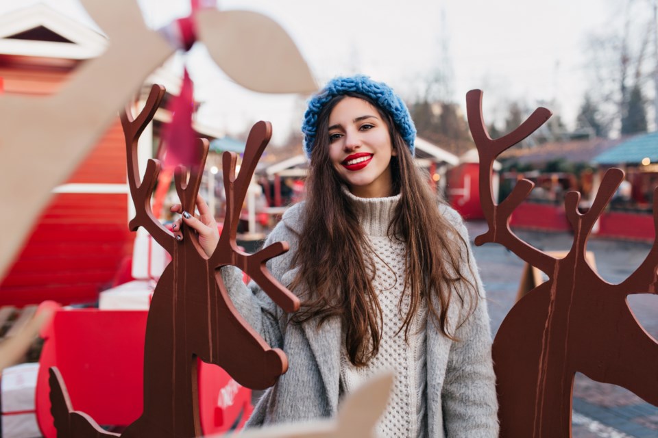 ecstatic-dark-haired-female-model-enjoying-christmas-themed-amusement-park-outdoor-portrait-glad-girl-knitted-blue-hat-posing-near-holiday-decoration-winter