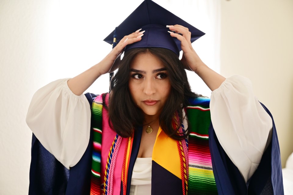 GREELEY, CO - MAY 7: Maria Bocanegra Tejeda, 22, puts on her graduation gown and cap for the 2022 University of Northern Colorado graduation ceremony at her home in Greeley, Colorado on Saturday, May 7, 2022. (Photo by Hyoung Chang/The Denver Post)

COLab