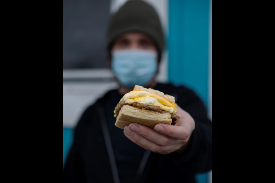 Owner of Biscuit at Mike's Mike Simuns holds a sausage, egg and cheese biscuit sandwich on Jan. 14. Photo by Ali Mai