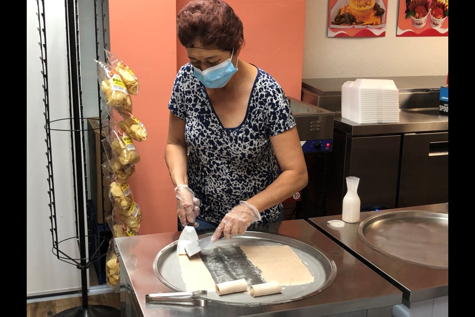Lety Tinoco, mother of Tutti Fruitti owner Arely Tinoco, carefully rolls homemade ice cream on freezer plate.