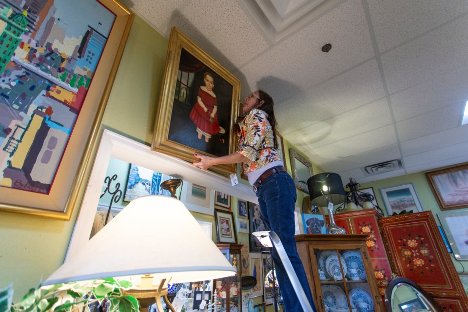  Longmont consignment store Fabulous Finds owner Clarissa Edelen hangs a painting inside of the furniture unit at 600 S Airport Rd. Photo by Ali Mai 