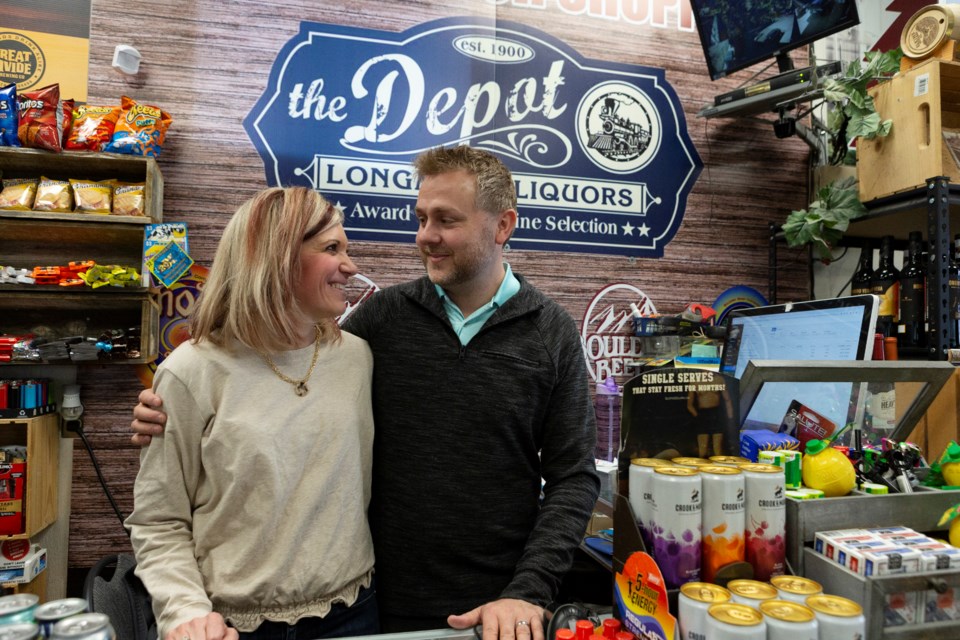Stephanie and Chris McGilvray, owners of Longmont Liquors, smile at eachother behind the store counter on Apr. 5. The Longmont couple opened their small business 10 years ago. Photo by Ali Mai | Longmont Leader