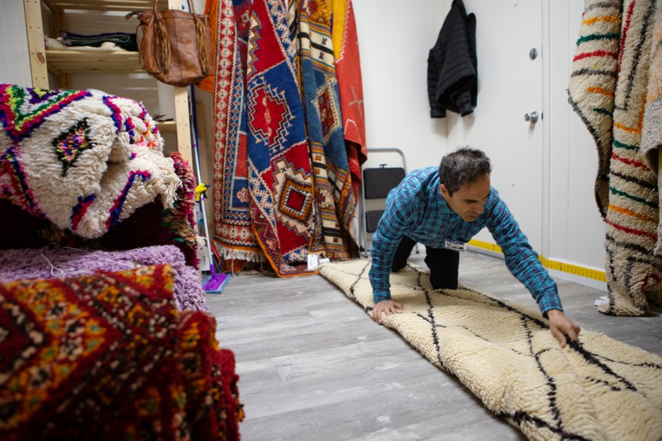 Hakim Ghabour, owner of Moroccan Rugs and Gifts, folds a  Beni Ourain tribal rug. Photos by Ali Mai 