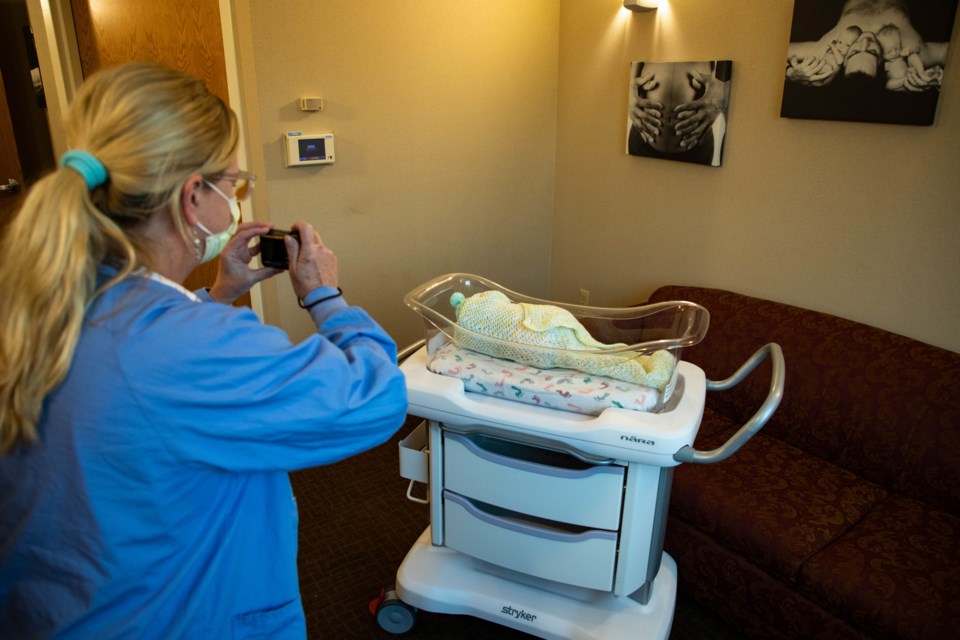 LUH Maternity nurse Robin Shivery taking a photo of a baby in a bassinet for the family