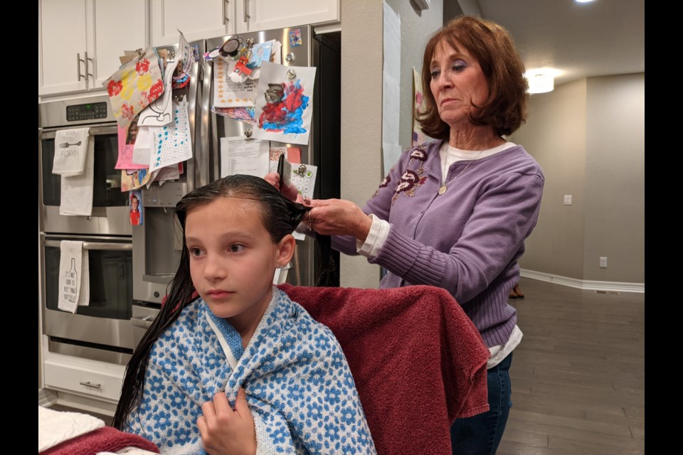 Professional delouser Linda Holmes combs through the hair of 8-year-old Huntley Marker on a weeknight in late October in the girlâs home in Parker, Colorado. Business is back up for Holmes and other nitpickers after a lull during the height of the pandemic. (Rae Ellen Bichell/KHN)