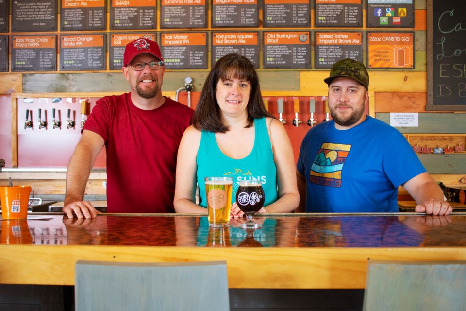 Left to right: 300 Suns Brewing Co-owners Dan and Jean Ditslear and Burger Nomad owner Nate Say stand behind the bar of the Longmont tasting room on June 23. Photo by Ali Mai | ali.mai.journo@gmail.com
