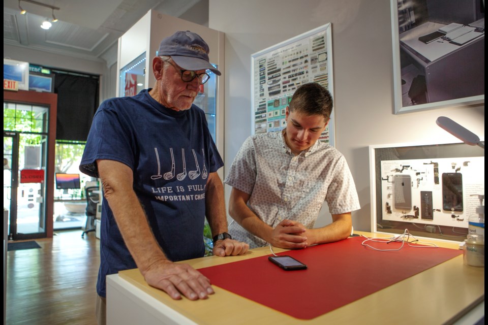 Senior technician at CO-TechPoint Jackson Guthrie(right), helps a customer Bill Sharp with his phone on June 30 at the Longmont tech store. Guthrie is 18 years old and a recent graduate from Mead High School. Photo by Ali Mai | ali.mai.journo@gmail.com