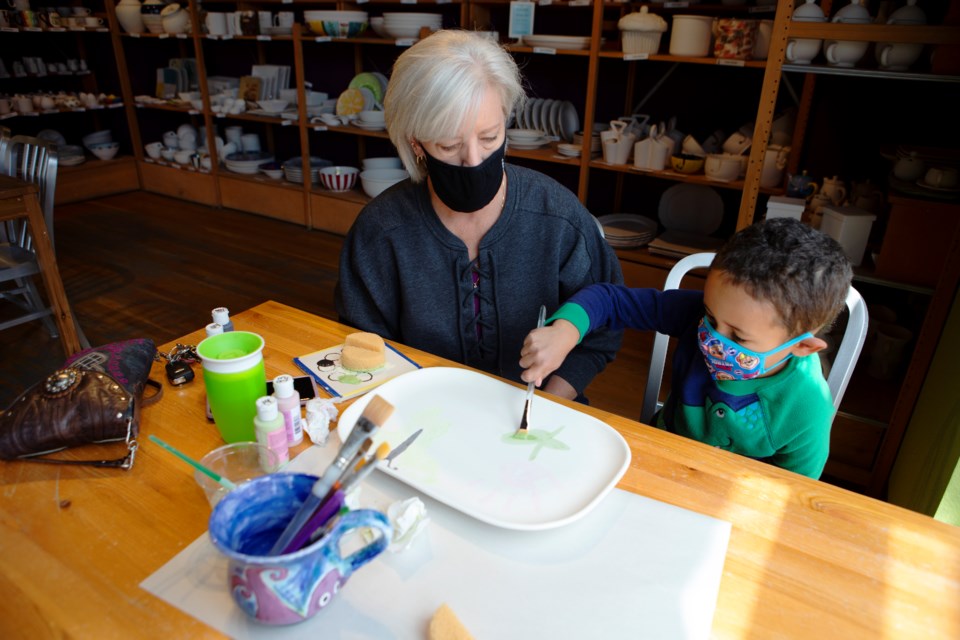 Customer Judi Diederich helps her grandson Gabriel, 3-years-old, paint a tray to give to his mom for Motherâs Day at Crackpots on April 28. Photo by Ali Mai | ali.mai.journo@gmail.com