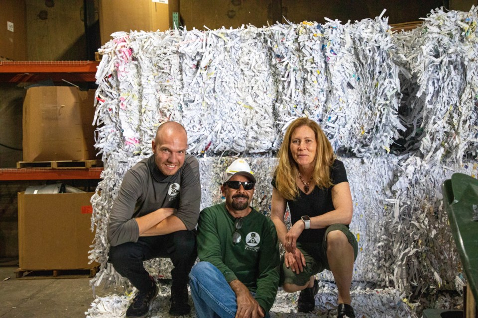 (L to R) Operations manager Brandon Wilkes, warehouse manager Jesus Medina and Green Girl owner Bridget Johnson pose on bales of shredded paper.