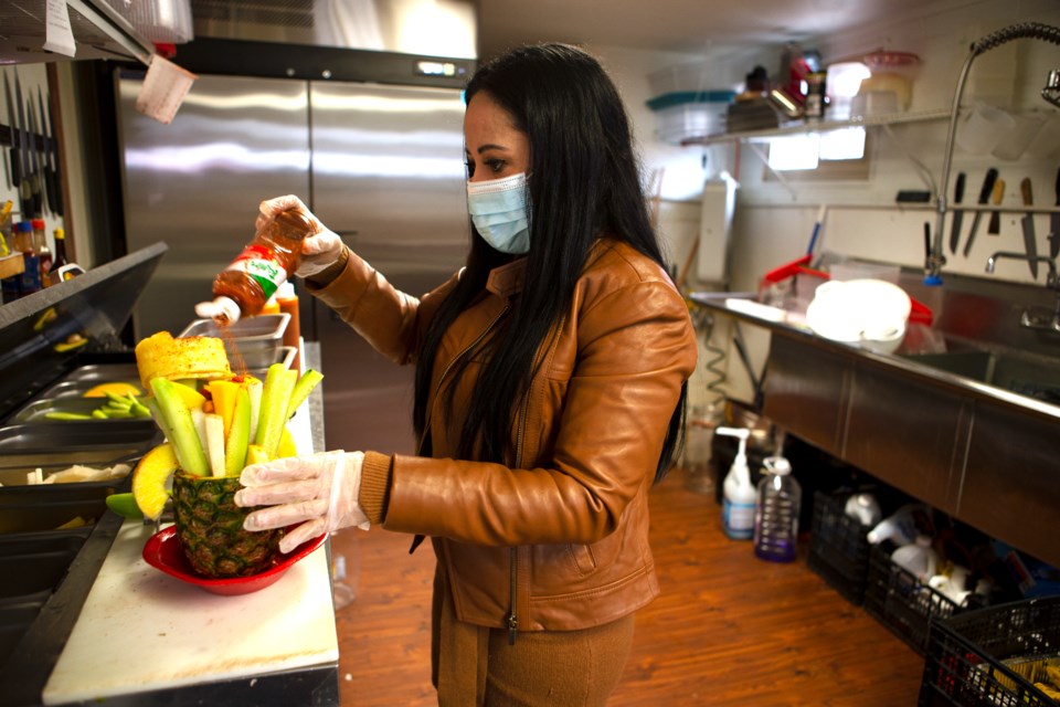 Haydee Caraveo Vasquez, owner of Oasis Fresh Fruit and More, makes one of the restaurantâs signature dishes Pina Locuaz, a large fruit assortment in a pineapple, on March 30. Photo by Ali Mai | ali.mai.journo@gmail.com