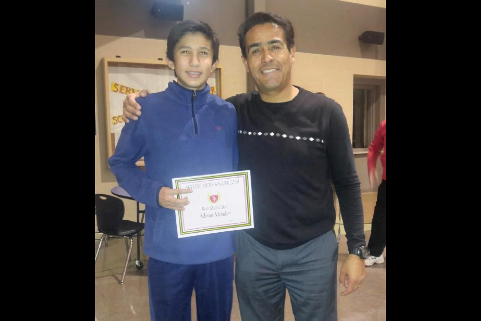 Adrian Mendez receiving an award from Skyline High School for "The Best Middle-fielder" in soccer. Pictured with soccer coach Luis Chavez.