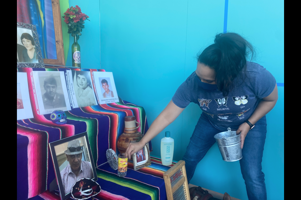 Moreno's daughter adds items to the Valenzuela family's altar for Día de los Muertos. 