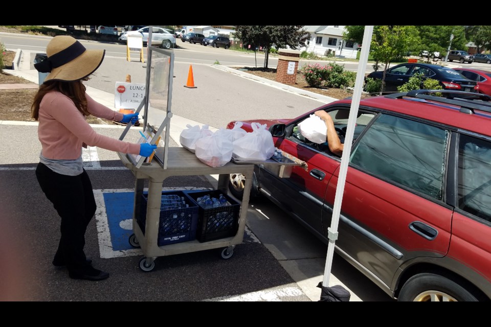 A volunteer hands out lunch in the OUR Center parking lot on Wednesday.
(Photo by Monte Whaley)