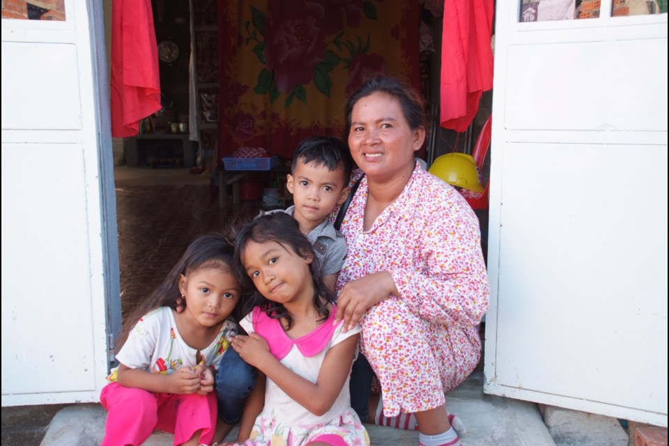Family sitting in the doorway of their new home in Cambodia