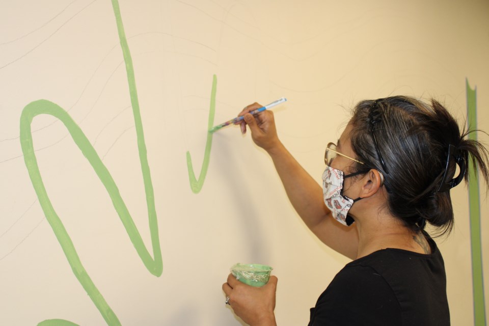 Elaine Waterman putting the beginning touches on the food line mural