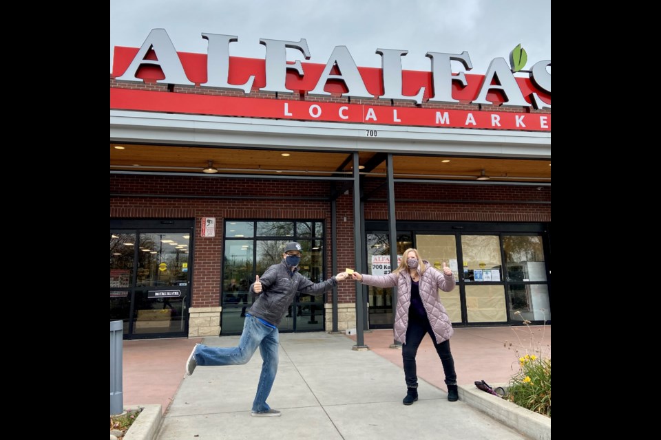 Chris Epp and Maria West exchange $100 Alfalfa's Market gift card in front of Longmont location. (Photo by Matt Barnett)