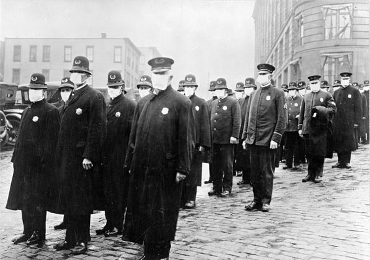 Policemen in Seattle, Washington, wearing masks made by the Red Cross, during the influenza pandemic, December 1918. 
(National Archives)
