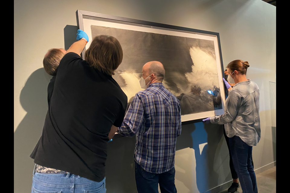 Staff at the Longmont Museum work together on Monday to hang a piece of art to be featured in the new exhibit, Washi Transformed: New Expressions in Japanese Paper. 