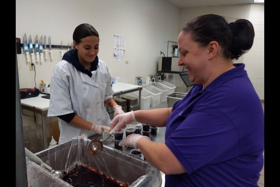 Erie High School senior Averie Esparza preps for lunch with kitchen manager Tia Jensen. 