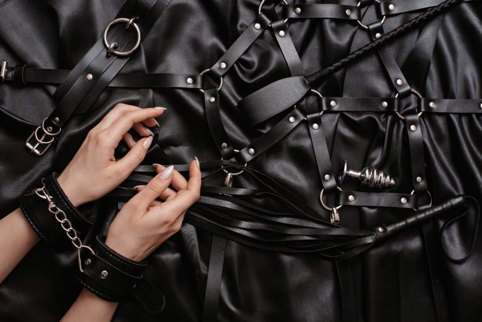 women-s-hands-handcuffs-dark-silk-sheet-adult-toys