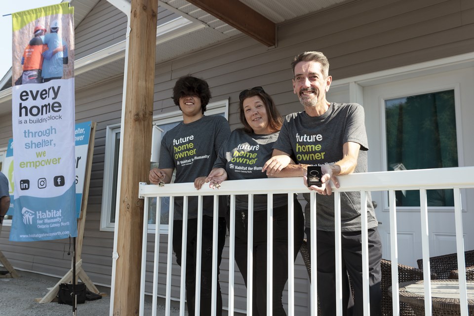 (left to right) Aiden Sutton, his mother Shannon Sutton, and her spouse John Steel were recipients of ceremonial keychains to accompany the keys of their new affordable home in Midland, courtesy of Habitat for Humanity Ontario Gateway North.