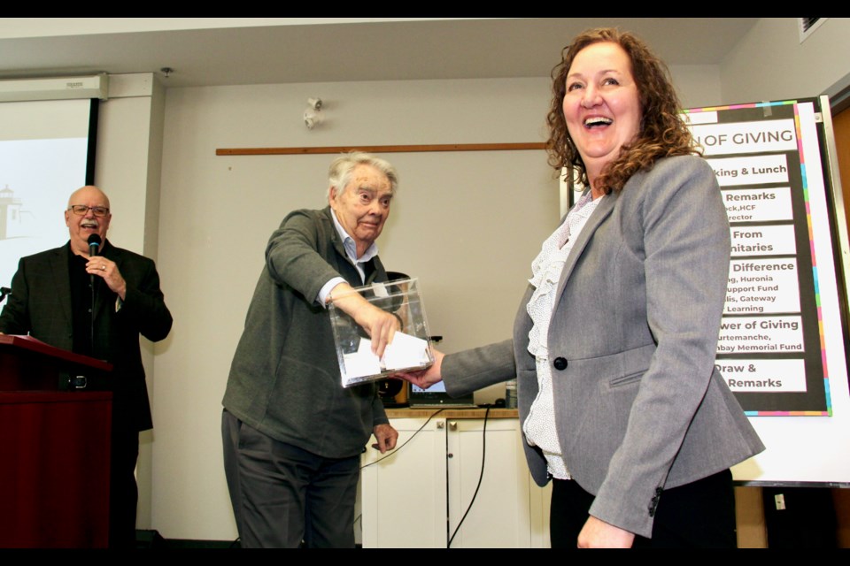 Huronia Community Foundation Board President Susan Lalonde-Rankin laughs as founding board president John Gammell draws a prize winner while Scott Warnock, executive director, looks on at the recent Celebration of Giving. 