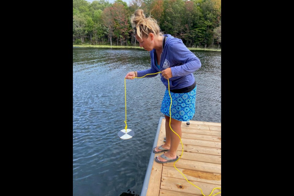 A Shore Watch volunteer takes a water clarity reading using a Secchi disk in Honey Harbour.