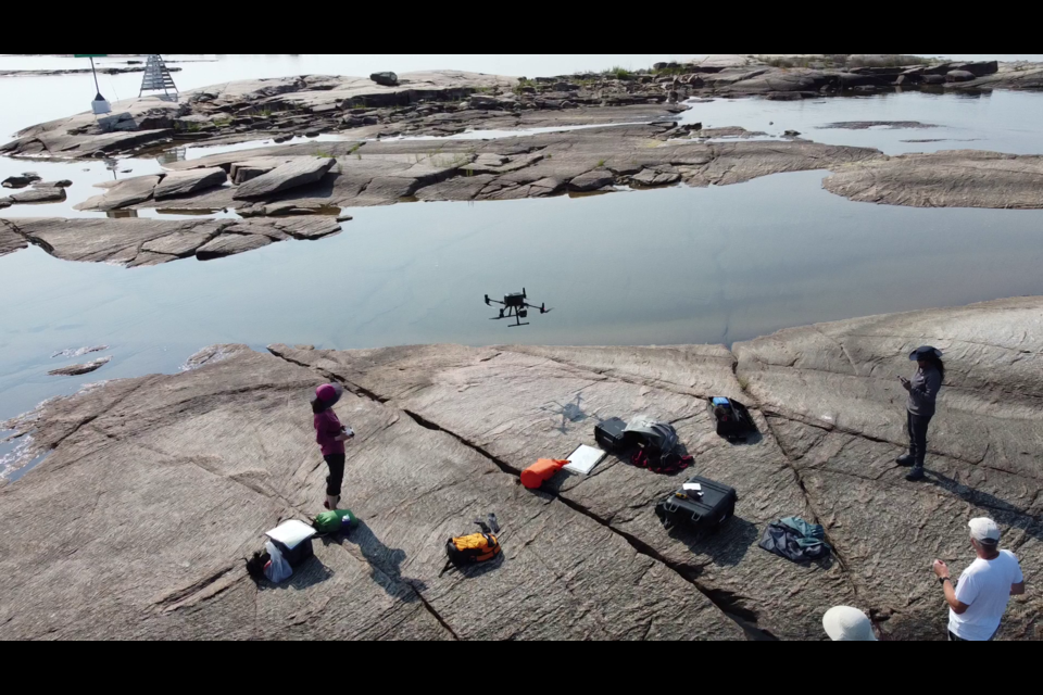 Geologist Kirsten Kennedy, left, is seen operating the LiDAR equipped drone as part of her geo-cultural mapping of Georgian Bay research project.