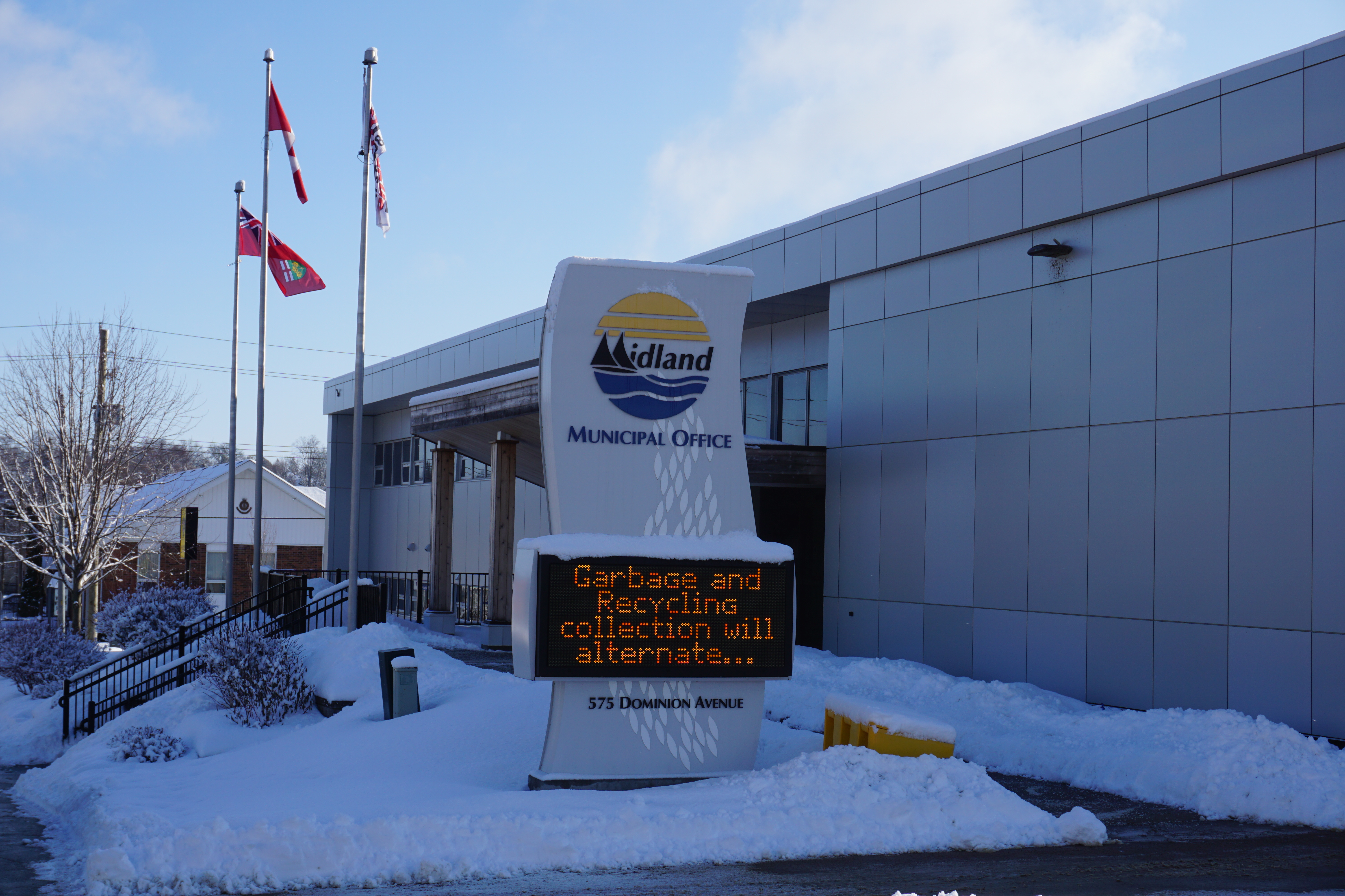 Town of Midland municipal office front entrance, with a message on a scrolling marquee on a large sign for the office.