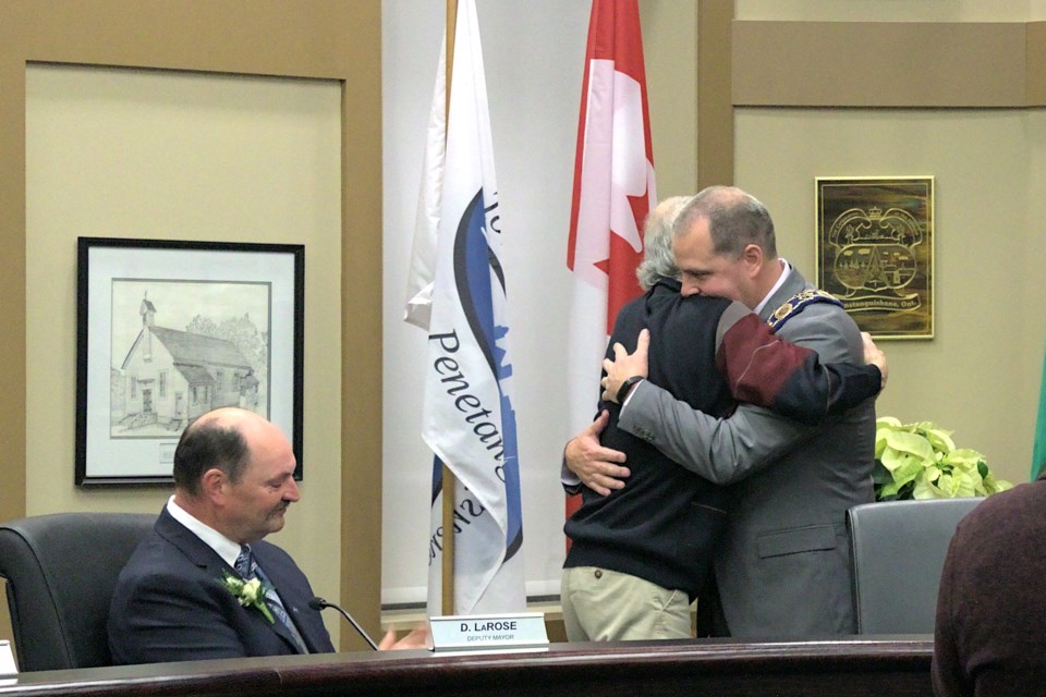 Mayor Doug Rawson (right) shared an emotional hug with his father Doug Rawson Sr. after receiving the mayor's chain of office around his neck. Fellow council members including Deputy Mayor Dan LaRose (left) and audience attendees watched during the inauguration ceremonies of Penetanguishene 2022-2026 council.