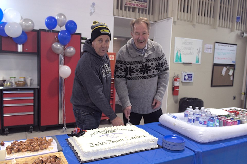 Patrick Murray (left) and Mike Power cut the cake during the celebratory grand opening of the John Power Centre on Newton St. The volunteer-built facility will provide grooming and maintenance operations for regional 'C' trails, in honour of the man who founded the Ontario Federation of Snowmobile Clubs in Victoria Harbour in 1967.