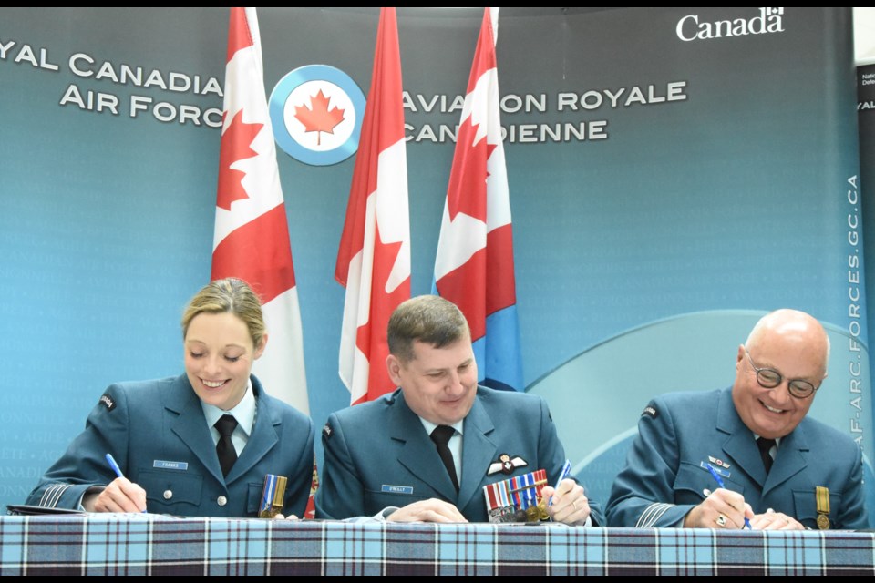 Lisa Franks, Col. Denis O'Reilly and Bert Olson sign documents during a handover ceremony at 15 Wing that installed Franks as the new honorary colonel. Olson is the outgoing honorary colonel and served for four years. Photo by Jason G. Antonio
