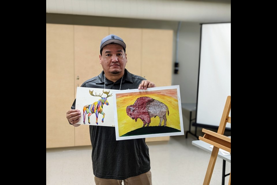 Artist Kevin Wesaquate with two of his artworks