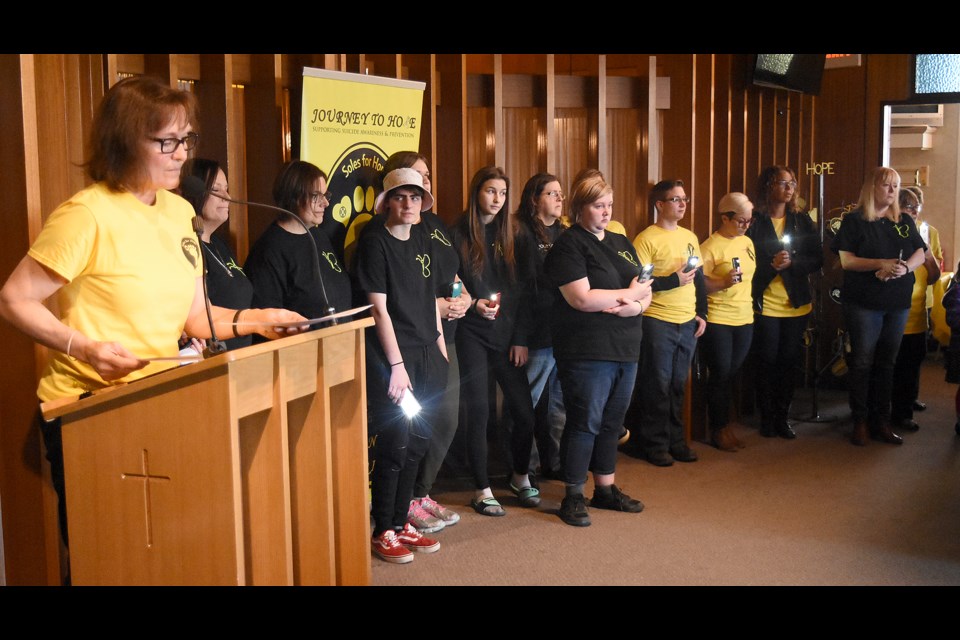 Journey to Hope volunteers light their cameras as Della Ferguson reads the role call of those lost to suicide during the 2019 event.