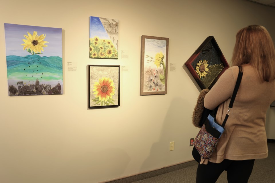 A visitor browses "Sunflower Power", the Art Guild's 2022 MJMAG exhibition honouring Ukrainians displaced by Russia's invasion. The sunflower is Ukraine's national flower