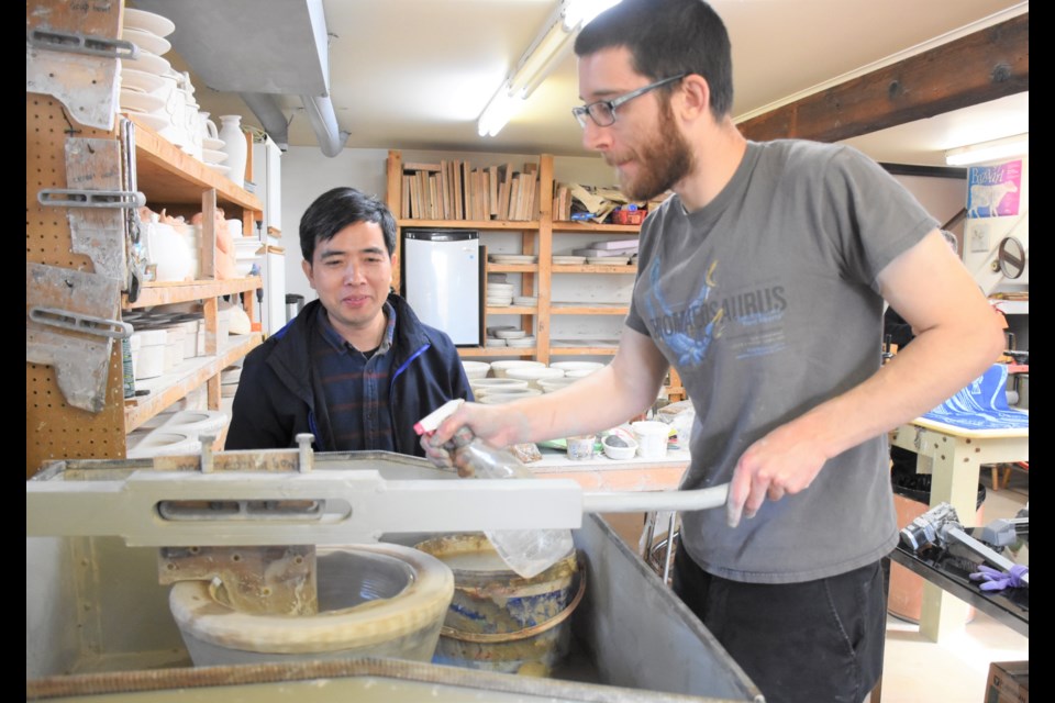 Art lover Mike Yang (left) watches Devon Dietrich use a jolly jigger machine to create a clay mould, at Parsons Dietrich Pottery. Photo by Jason G. Antonio