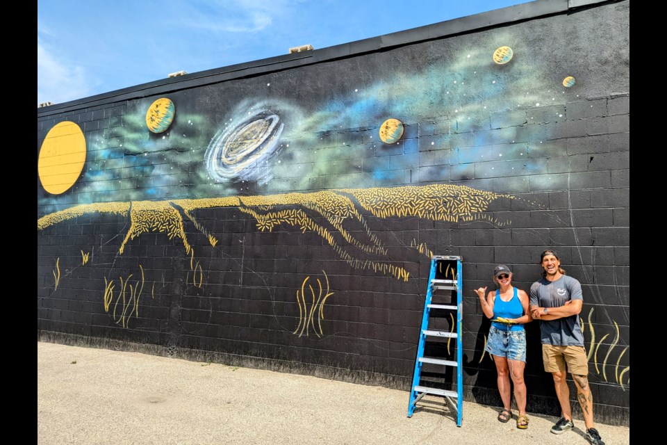 Carly Jaye, pictured here with Boh's owner Brittan Calibaba, expects to finish her latest work of art by mid-August