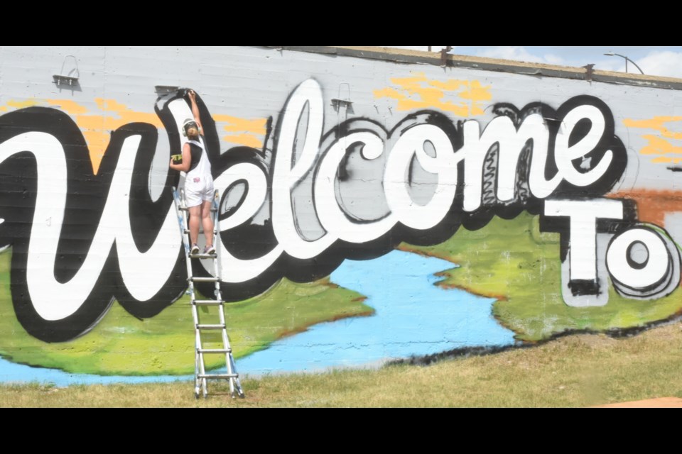 "Welcome to ... ." One side of the mural takes shape under the steady hand of Carly Jaye Smith. Photo by Jason G. Antonio