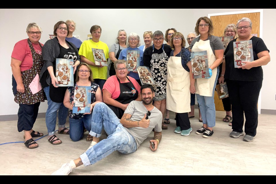 Antonis Tzanidakis joins members of his mixed-media workshop for a group photo after completing their projects.