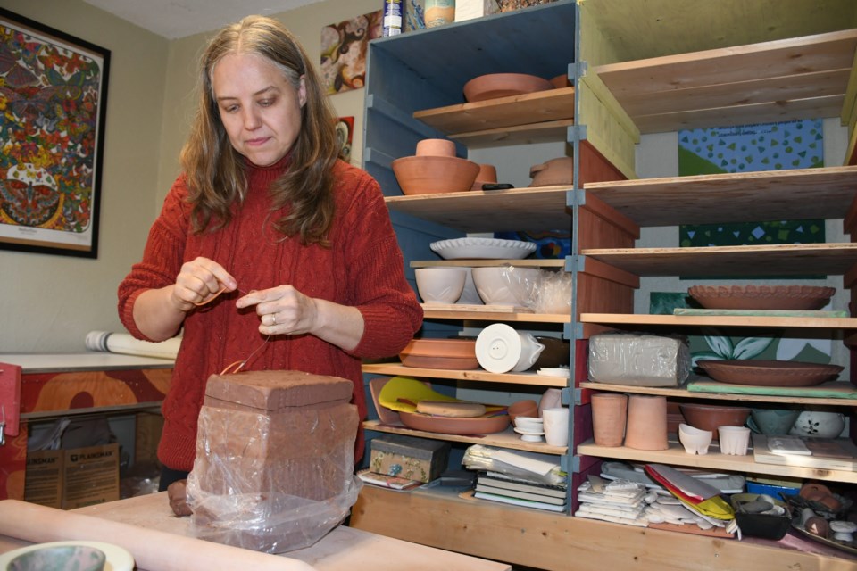 Beth Barrett prepares to cut a large block of clay. Photo by Jason G. Antonio