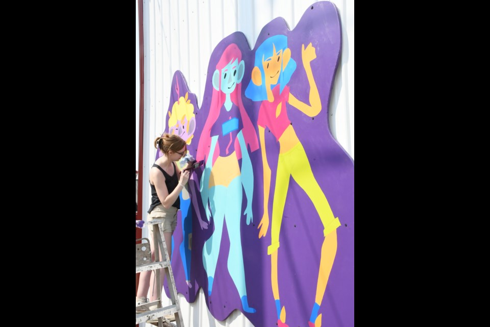 Emma Rowlinson, a Grade 12 student at A.E. Peacock Collegiate, puts finishing touches on one of the last panels of the mural. Rowlinson was responsible for the artwork's colour scheme. Photo by Jason G. Antonio